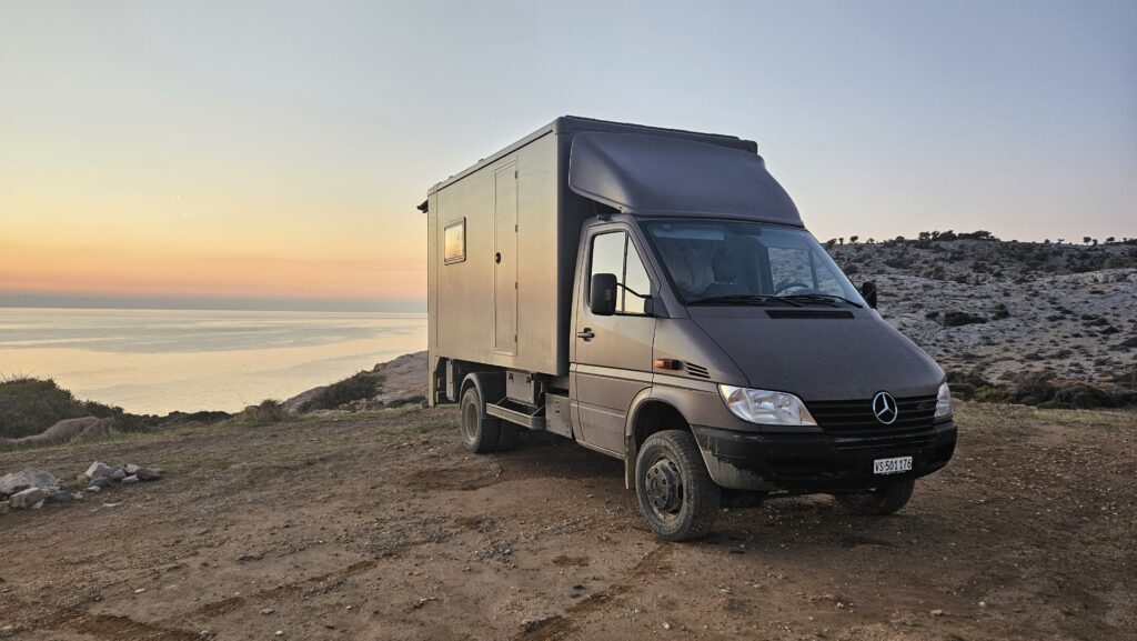 Camion aménagé face à la mer au coucher du soleil
